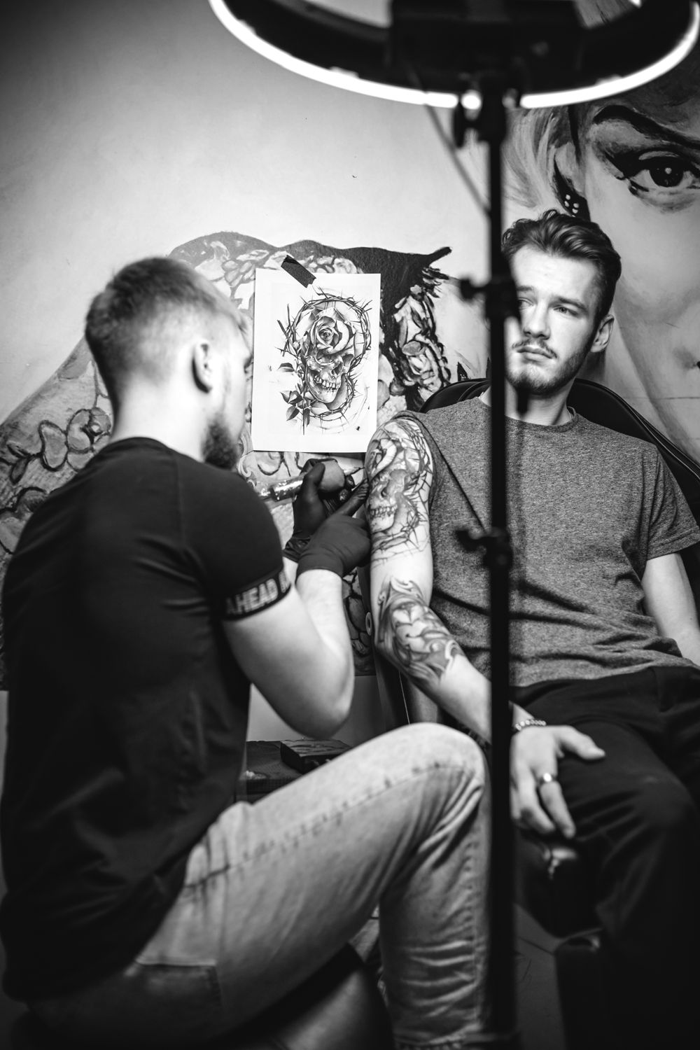 Nikita tattooing a skull and rose design on a client’s arm