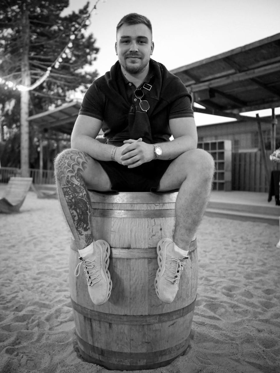 Nikita, tattoo artist, sitting on a barrel